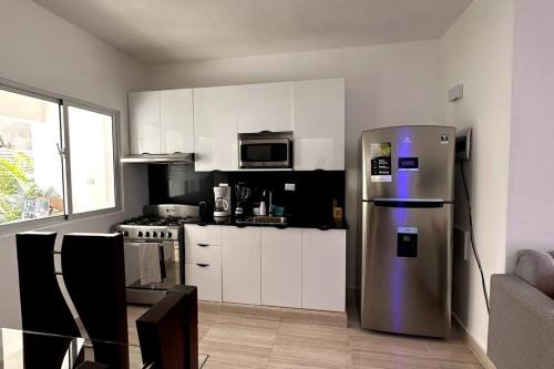 een keuken met een roestvrijstalen koelkast en witte kasten bij Brand New Apt in PUNTA CANA. in Punta Cana
