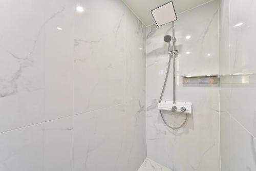 a bathroom with a shower with white marble walls at Hotel February Tongyeong Jukrim in Tongyeong