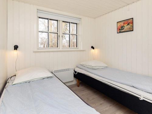 Holiday home Martofte XI في Martofte: سريرين في غرفة بجدران بيضاء ونوافذ
