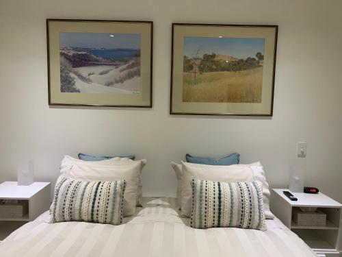 a bedroom with two pictures above a bed with pillows at SEABREEZE at Victor Harbor in Victor Harbor