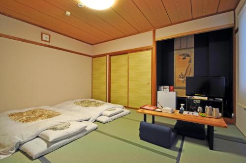 two beds in a room with a desk and a tv at Annex Hotel Abe in Kurihara