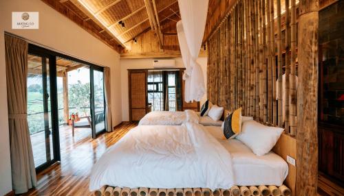 2 Betten in einem Schlafzimmer mit großen Fenstern in der Unterkunft Mường Lò Retreat Nghia Lo in Yên Bái