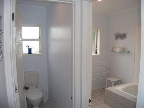 a bathroom with a toilet and a tub and a sink at Hosts on the Coast - Vista Verde in Pauanui