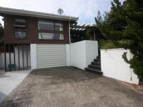 a house with a white fence and a garage at Hosts on the Coast - Vista Verde in Pauanui