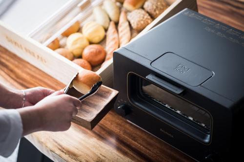 a person is putting something in aountersenalsenal of bread at Nest Hotel Hiroshima Ekimae in Hiroshima