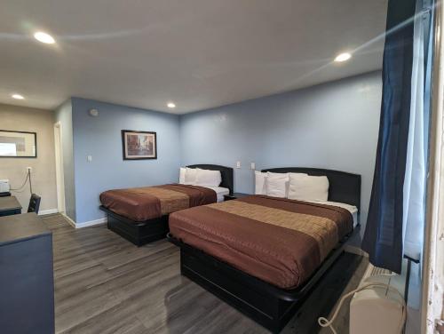 two beds in a hotel room with blue walls at BEST MOTEL on Historic Route 66, Barstow in Barstow