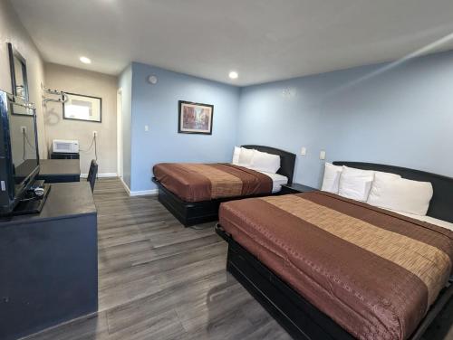 um quarto de hotel com duas camas e uma televisão de ecrã plano em BEST MOTEL em Barstow
