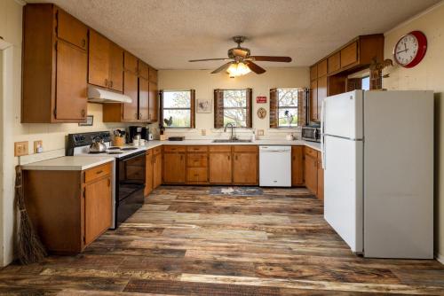 a kitchen with wooden cabinets and a white refrigerator at Stay on a 350-acre Cattle Ranch! Brazos River! Tubing! Petting zoo! in Weatherford