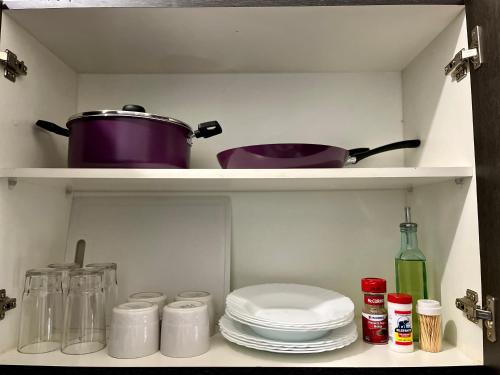 a kitchen shelf with plates and a pot and pans at Condominio en Playa del Carmen c/alberca in Playa del Carmen