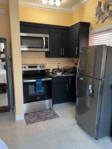 a kitchen with black cabinets and a stainless steel refrigerator at Negril Studio One in Negril