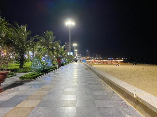 a walkway with palm trees and a street light at night at Hotel Hoàng Hưng Quy Nhơn in Quy Nhon