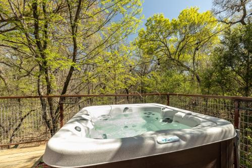 een hot tub op een terras met bomen op de achtergrond bij "Magical Treehouse" w spiral slide off the deck 350 acres on the Brazos River! Tubing! Petting Zoo! in Weatherford