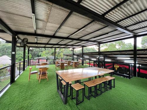 a pavilion with tables and chairs and green grass at PLAY at Lot 31 Eco Orchard Melaka in Sempang Sentul