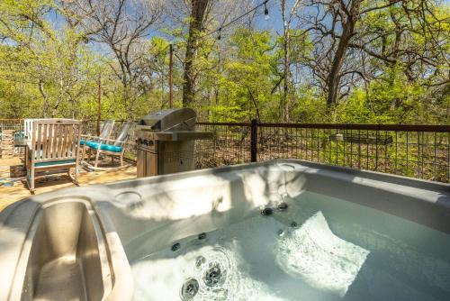 a jacuzzi tub in a backyard with a grill at Hobbit Treehouse with waterfall on the Brazos River! 350 acres! Tubing! Petting zoo! in Weatherford