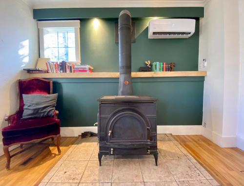 a wood stove in a living room with a chair at Family Summer House in the Eastern Townships in Ayer's Cliff