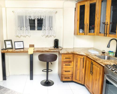 una cocina con armarios de madera y taburete. en Francis Nook Belle Garden Room, en San Juan