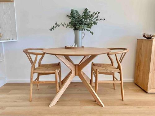a wooden table with two chairs and a vase on top at Alby’s - Cotton Tree in Maroochydore