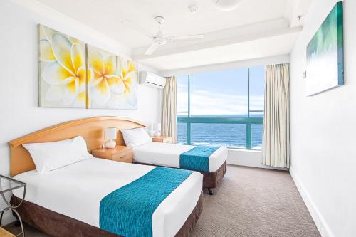 two beds in a hotel room with a large window at Crown Towers Resort - Private 3 Bedroom Apartment in Gold Coast