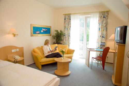 una mujer sentada en un sofá en una habitación de hotel en Hotel & Apartments Leugermann, en Ibbenbüren