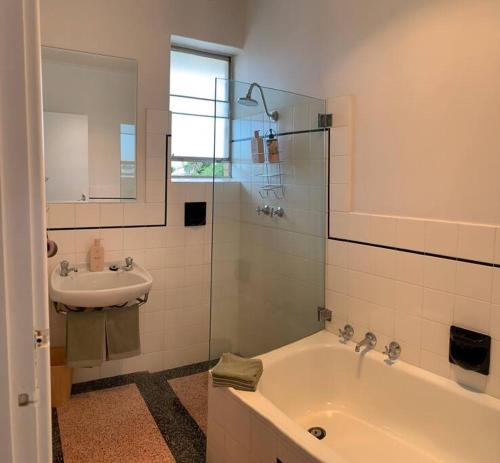 a bathroom with a sink and a tub and a mirror at Yarrumla Beach Lodge in Somerton Park
