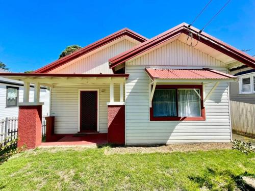a white and red house with a red door at Jasmine Cottage in Katoomba