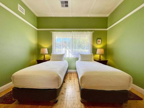 2 Betten in einem Zimmer mit grünen Wänden und einem Fenster in der Unterkunft Jasmine Cottage in Katoomba