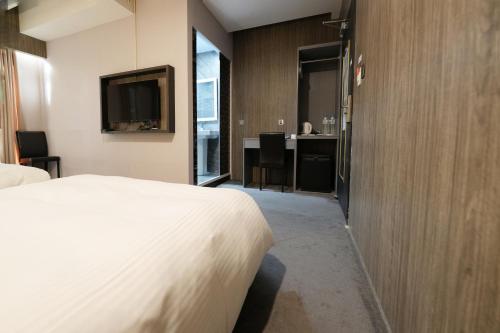 pokój hotelowy z łóżkiem i telewizorem w obiekcie Welove meworld Inn w Tajpej