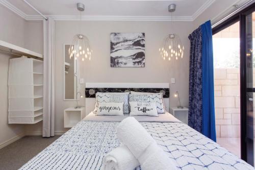 a bedroom with a white bed with blue curtains and chandeliers at Bambino 438 in Perth
