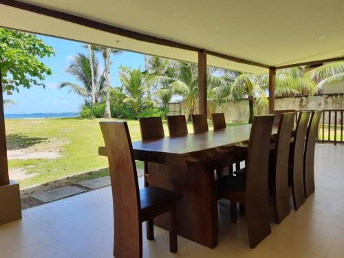 een houten tafel en stoelen met uitzicht op de oceaan bij Sunset Beach House Siargao in General Luna