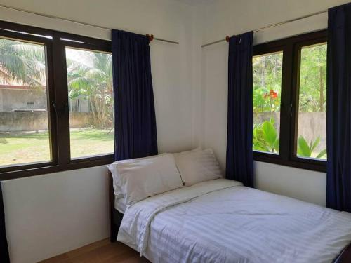 a bedroom with a bed and two windows at Sunset Beach House Siargao in General Luna