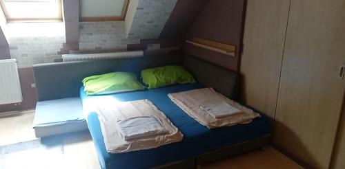 a blue bed with two green pillows on it at Levendula in Békéscsaba