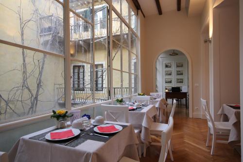 una sala da pranzo con tavoli bianchi e pianoforte di Residenza L'angolo di Verona a Verona