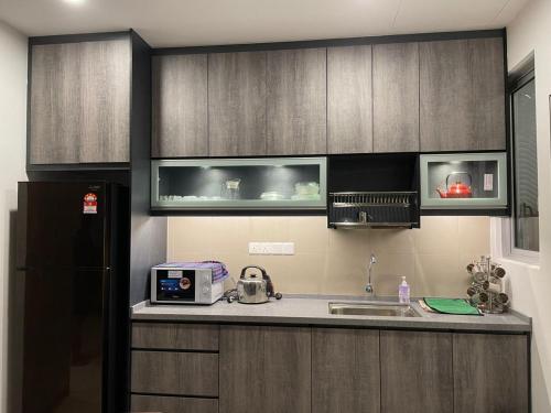 a kitchen with wooden cabinets and a sink and a refrigerator at SKY LAKE RESIDENCY, PUTRA PERDANA PUCHONG in Puchong