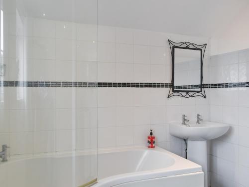 a bathroom with a sink and a tub and a mirror at Wisteria Cottage in New Milton