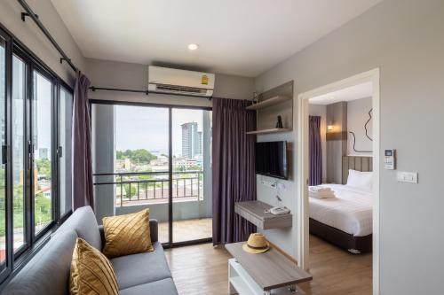 Habitación de hotel con cama y ventana grande en Horsehill Hotel Sriracha, en Si Racha