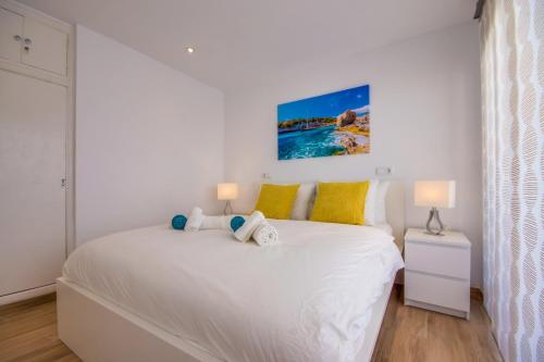 een slaapkamer met een groot wit bed met gele kussens bij Primavera in Port d'Alcudia