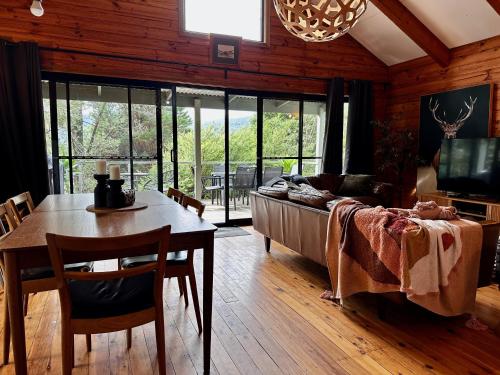 Kangaroo Valley Timber Cabin في كانجرو فالي: غرفة معيشة مع طاولة وأريكة وطاولة وكراسي