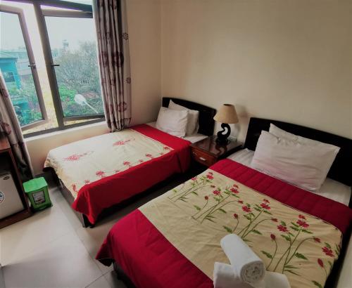 two beds in a room with a window at Frontier Hostel & Tours in Dien Bien Phu