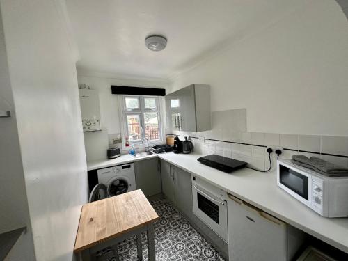 uma cozinha branca com um lavatório e um micro-ondas em Chic & Cosy Studio Apartment em Southampton