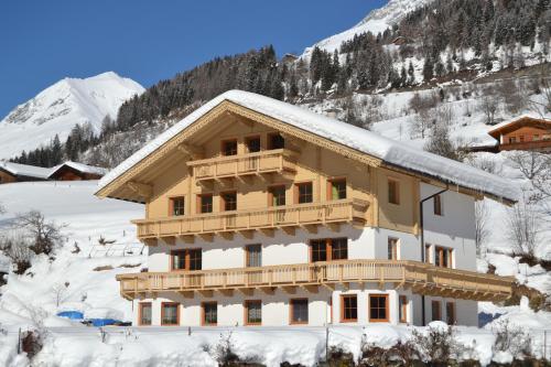 a building covered in snow with a mountain in the background at Apartment Santnerhof in Virgen