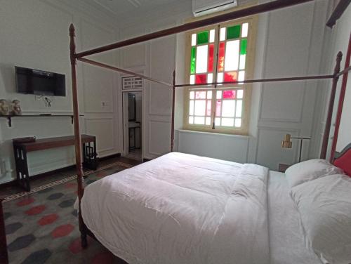 a bedroom with a canopy bed and a window at Mruyung Guest House Kota Lama Banyumas Mitra RedDoorz in Banyumas