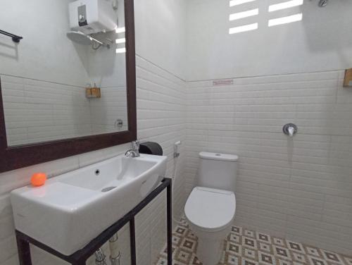 a white bathroom with a sink and a toilet at Mruyung Guest House Kota Lama Banyumas Mitra RedDoorz in Banyumas