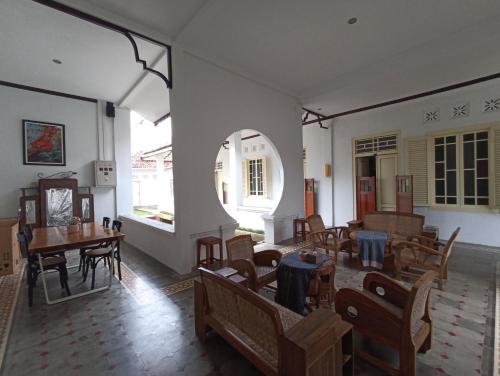 a room with tables and chairs and a room with windows at Mruyung Guest House Kota Lama Banyumas Mitra RedDoorz in Banyumas