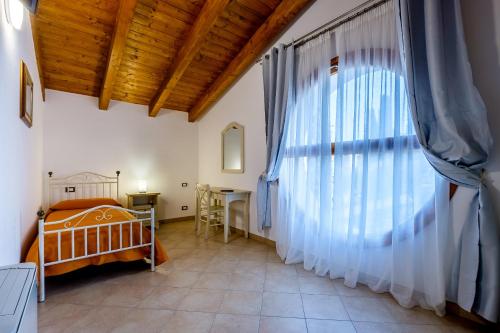 ein Schlafzimmer mit einem Kinderbett und einem großen Fenster in der Unterkunft Agriturismo i Merli in SantʼAmbrogio di Valpolicella