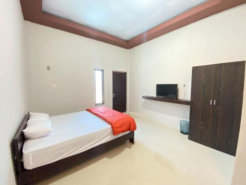 a small bedroom with a bed and a cabinet at Kanaan Guesthouse RedPartner in Manado
