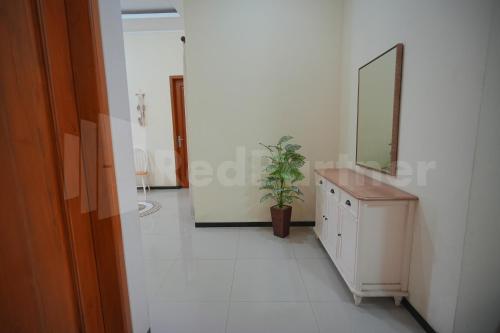 baño con espejo y tocador con planta en One & Quin Guest House Syariah Mitra RedDoorz, en Jenggrik