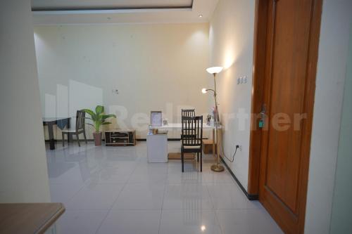 pasillo con mesa y sillas en una habitación en One & Quin Guest House Syariah Mitra RedDoorz, en Jenggrik