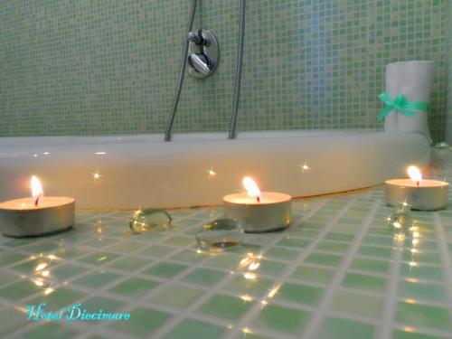 three candles sitting on the floor in front of a bath tub at Hotel Diecimare in Cava deʼ Tirreni