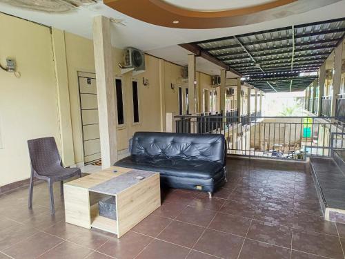a black leather couch and a table in a room at RedDoorz @ Al Muhajir Homestay Kendari in Kendari
