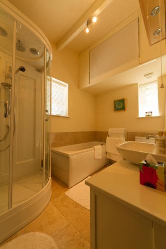 a bathroom with a shower and a sink and a tub at Pant Teg B & B in Bangor